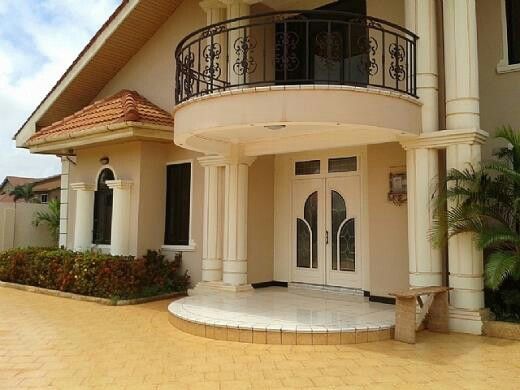 Elegant house entrance with curved balcony and double doors.